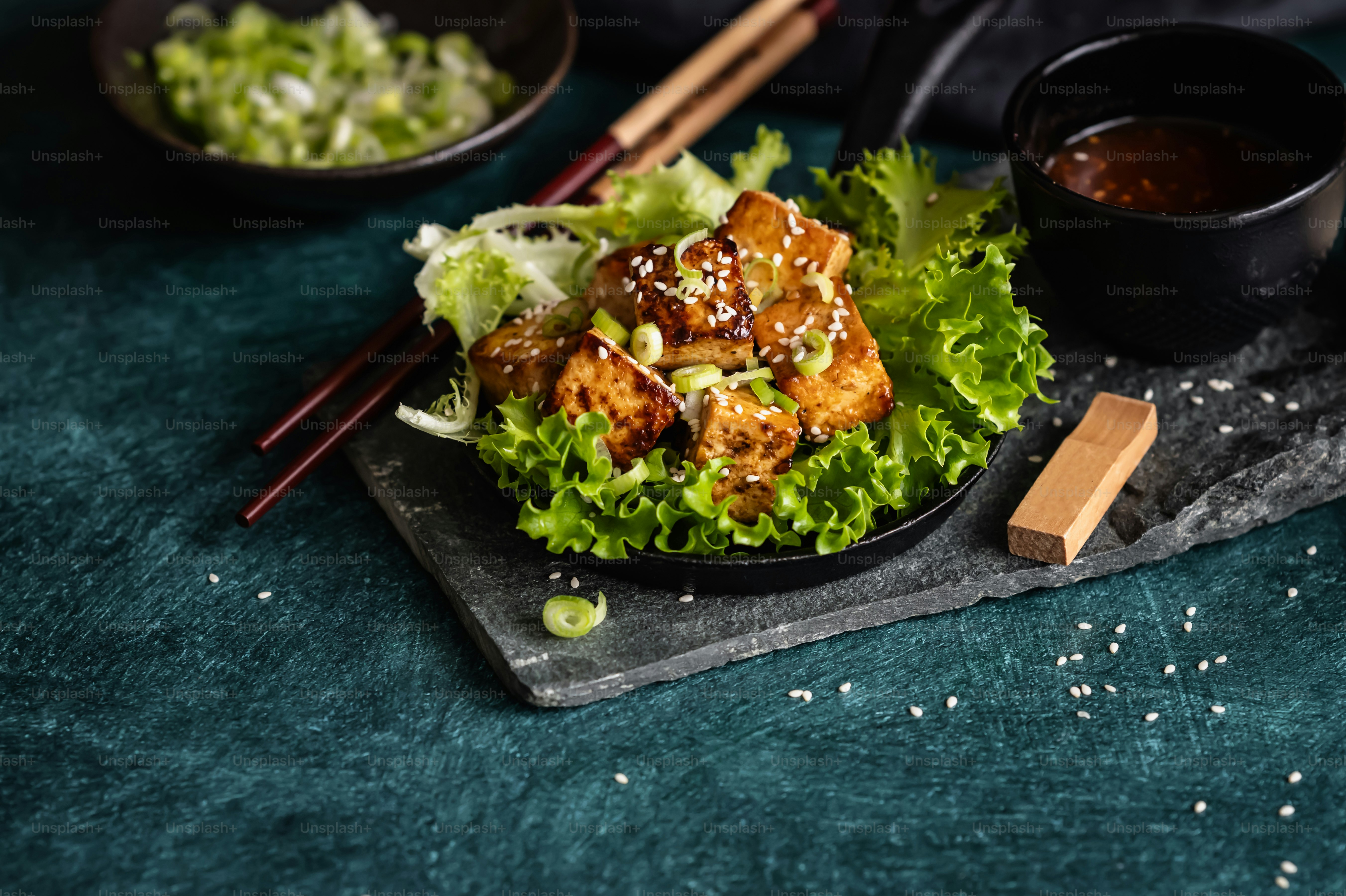 a plate of food with chopsticks and a bowl of sauce