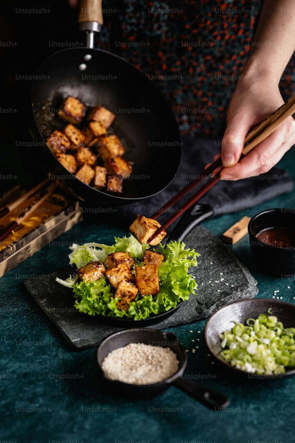 Una persona che cucina il cibo in un wok con le bacchette