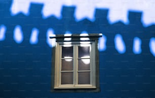 l’ombre d’une fenêtre sur un mur bleu