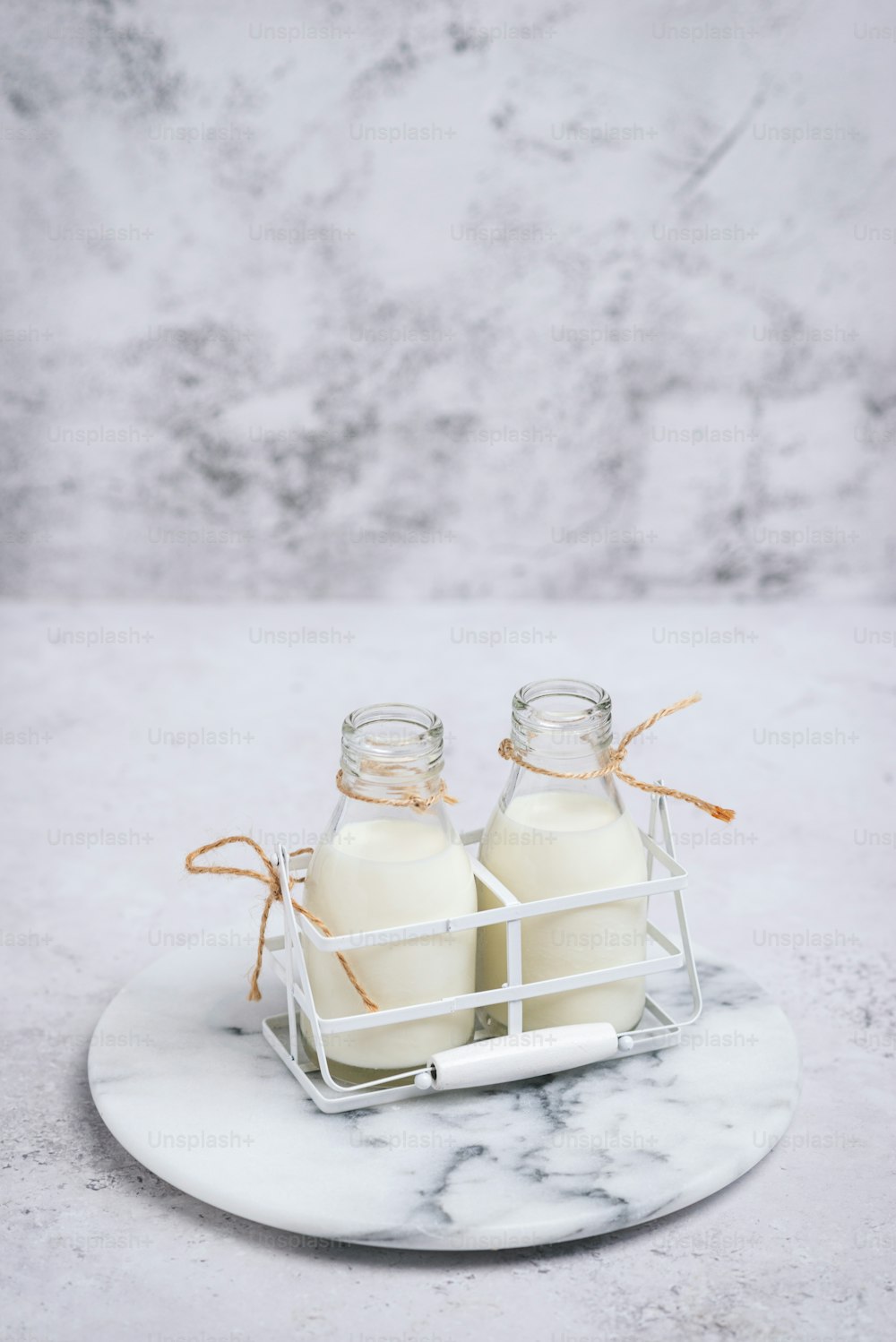 Dos botellas de leche sentadas en un plato de mármol