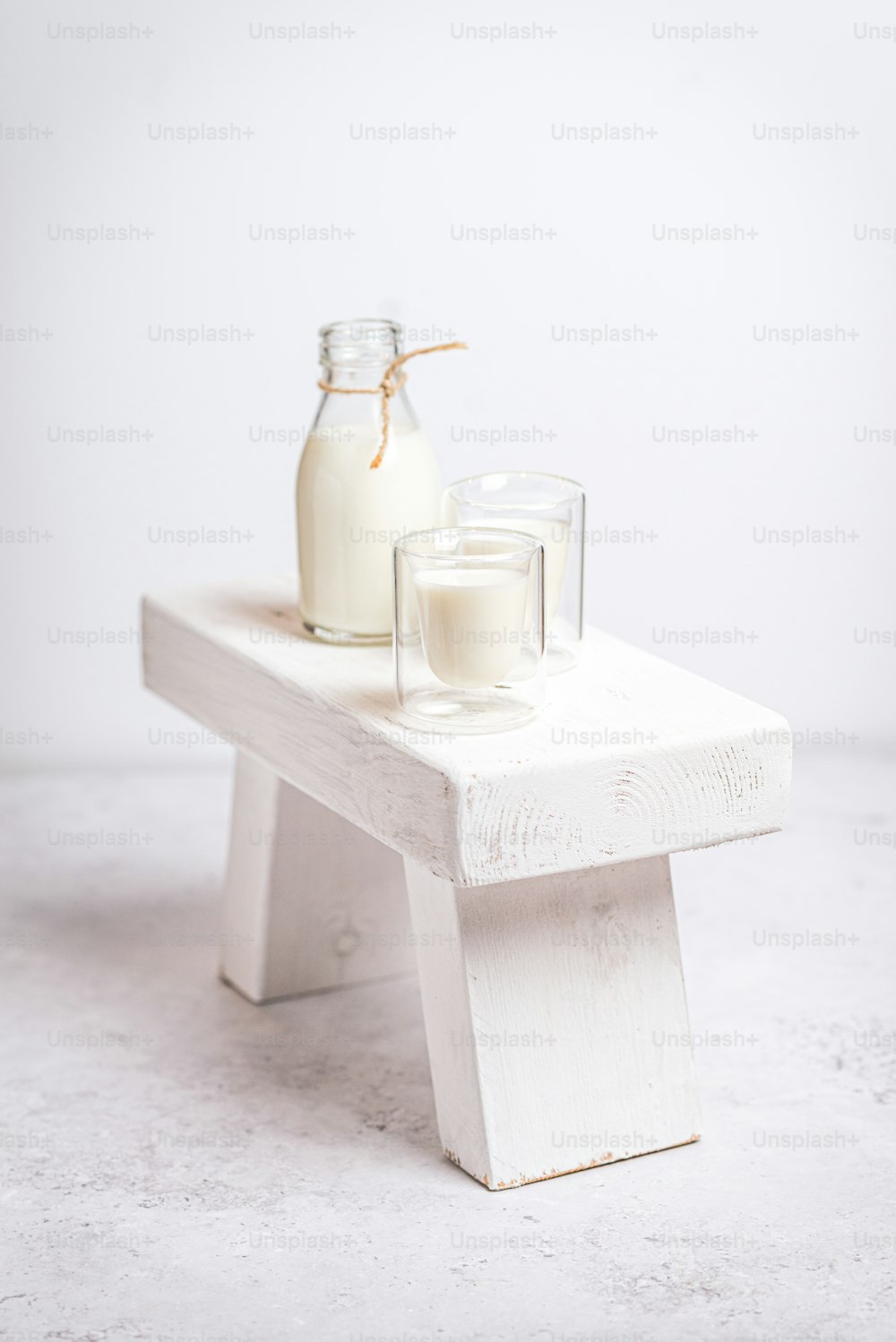 two glasses of milk sitting on a white bench