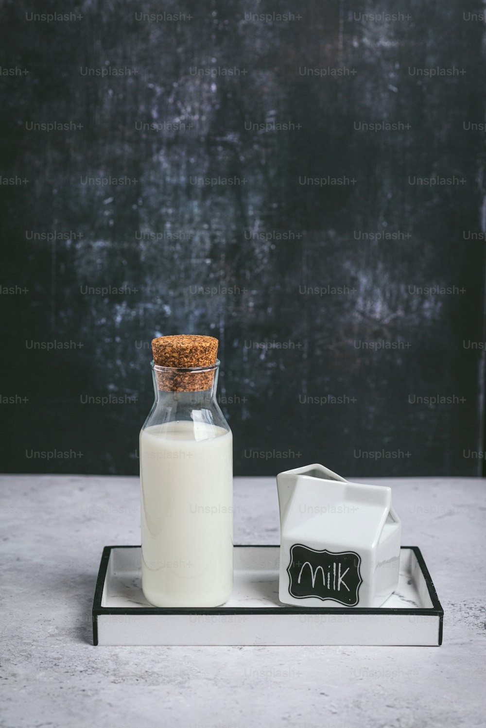 una botella de leche y un vaso de leche en una bandeja
