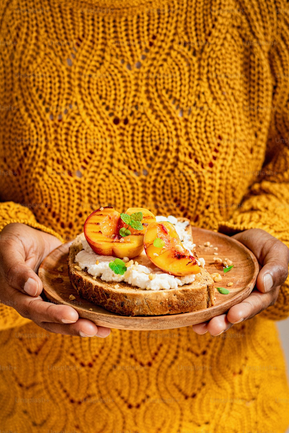 a woman in a yellow sweater holding a plate of food