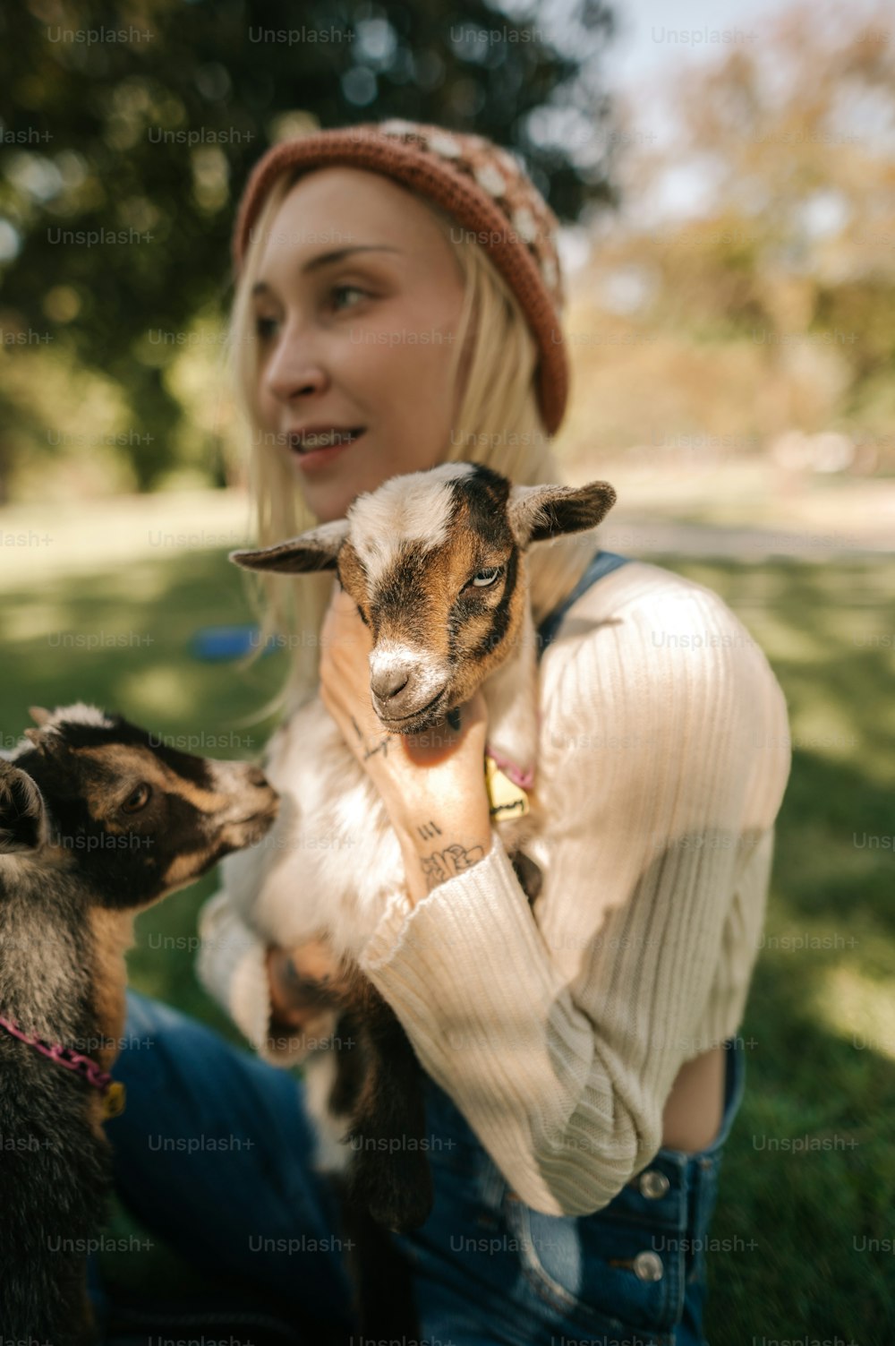uma mulher segurando um bebê cabra em seus braços
