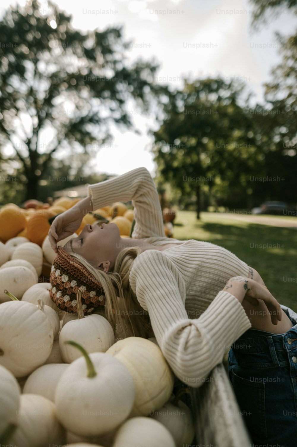 a woman laying on top of a pile of pumpkins