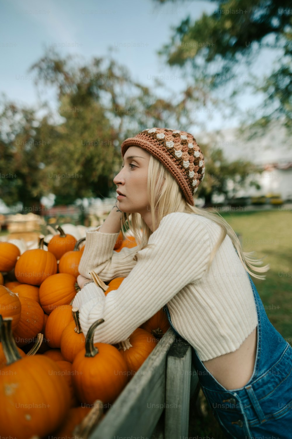 a woman leaning on a pile of pumpkins