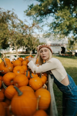 a woman leaning on a cart full of pumpkins