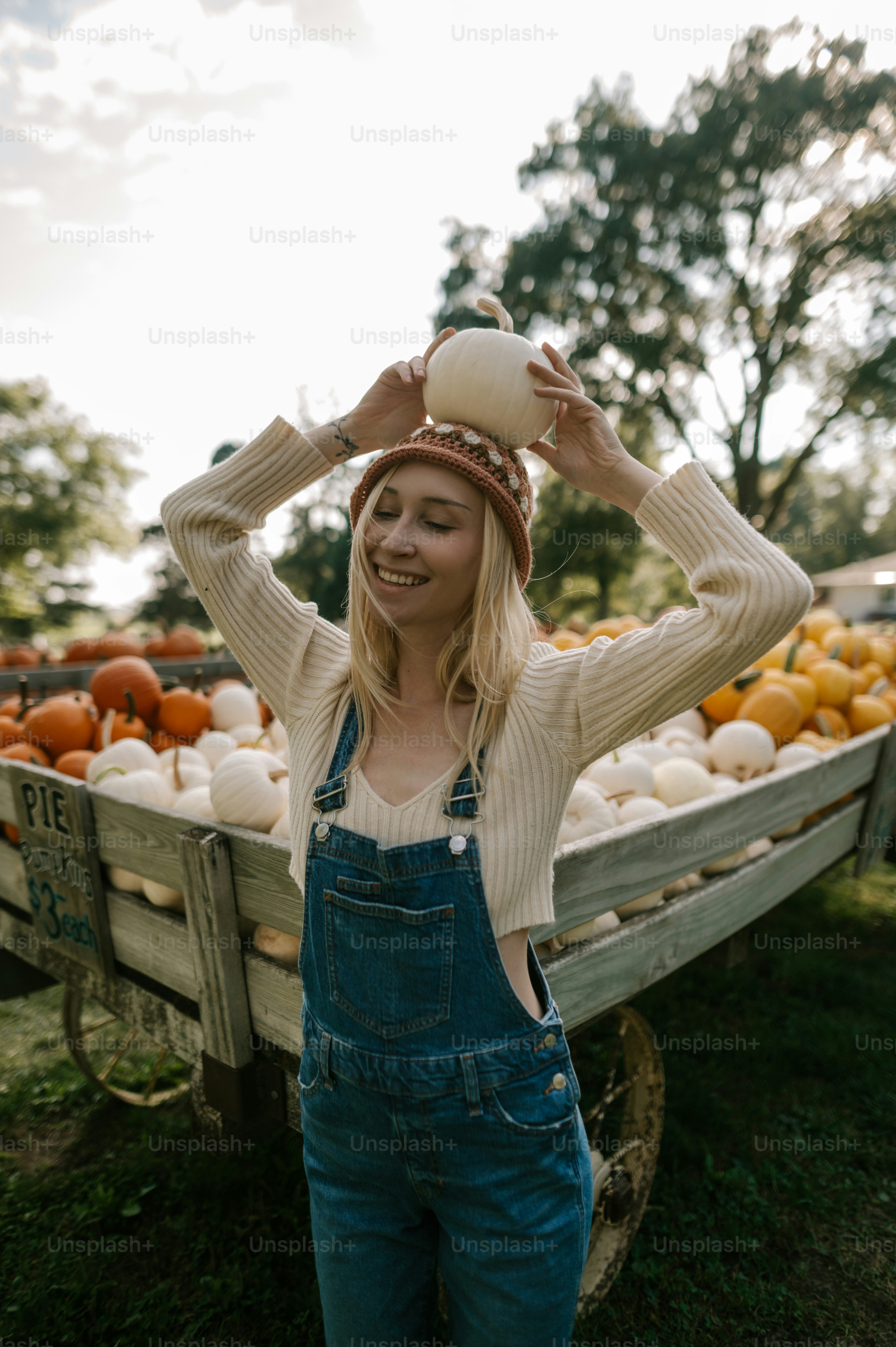 a woman standing in front of a wagon full of pumpkins