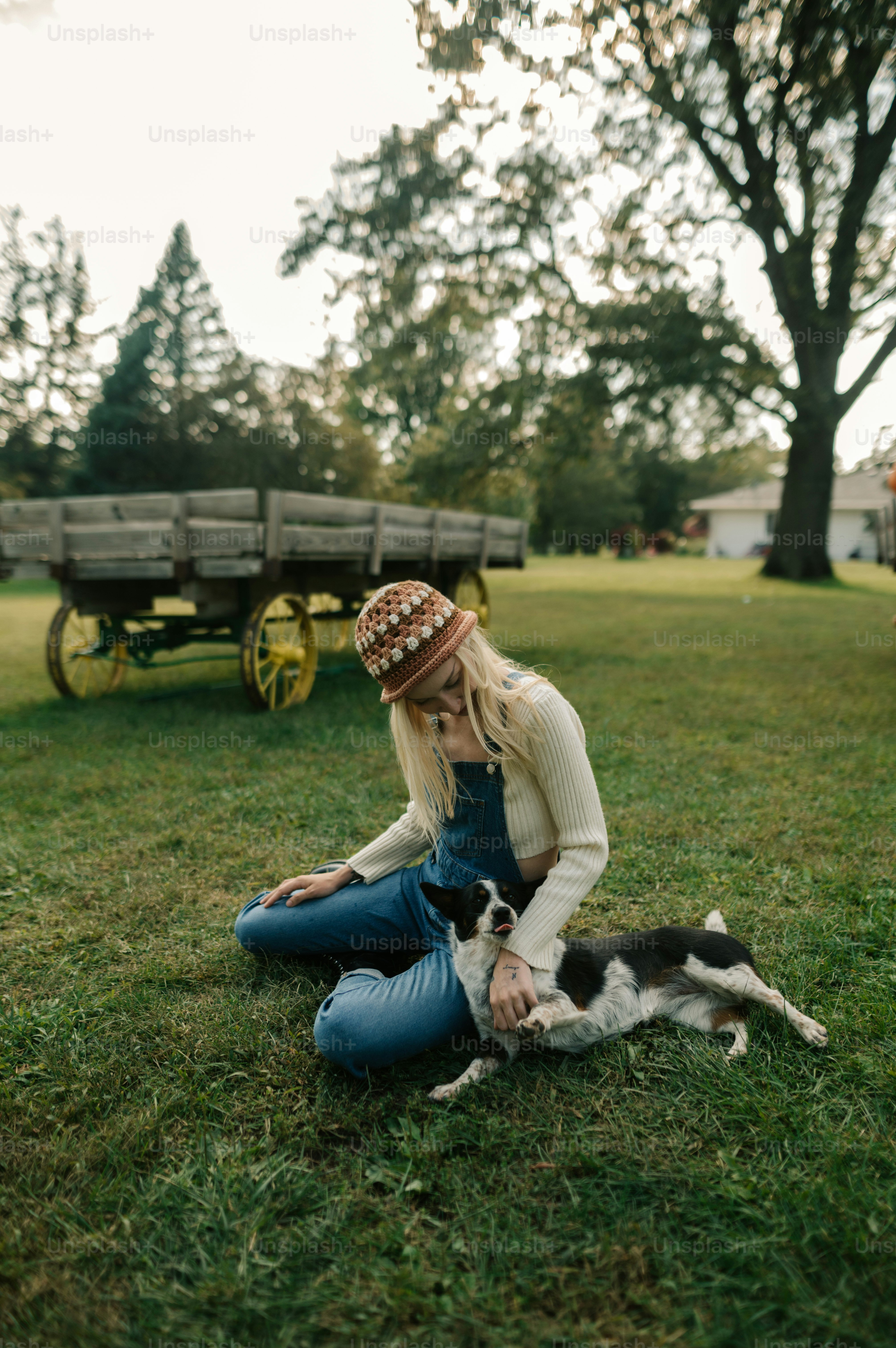 a woman sitting in the grass with a dog