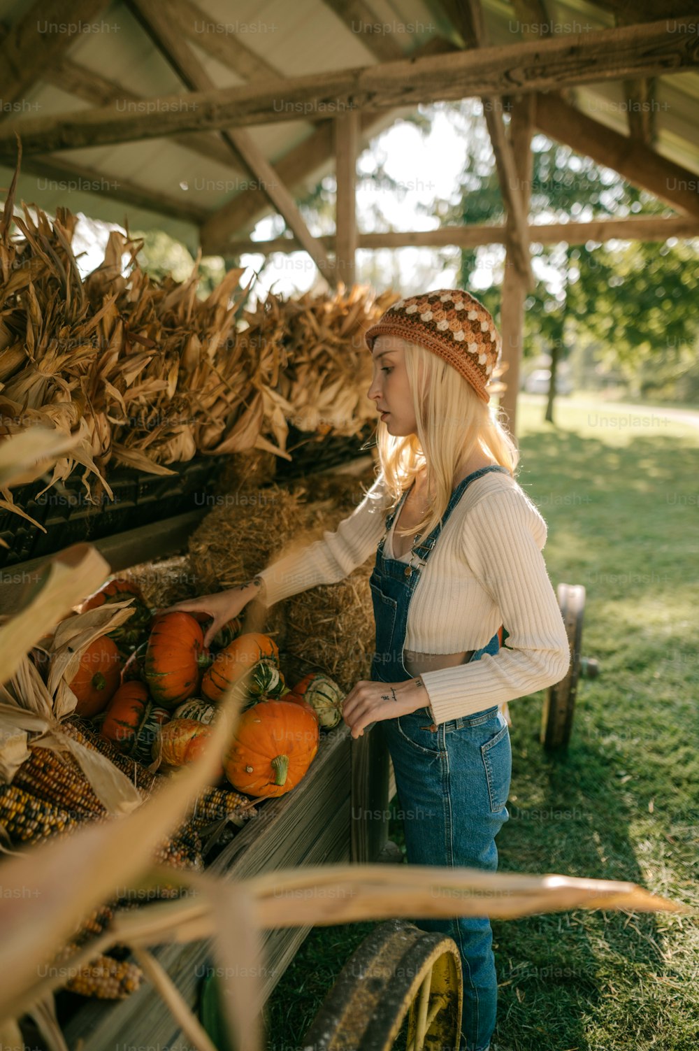 a woman standing next to a wagon filled with pumpkins