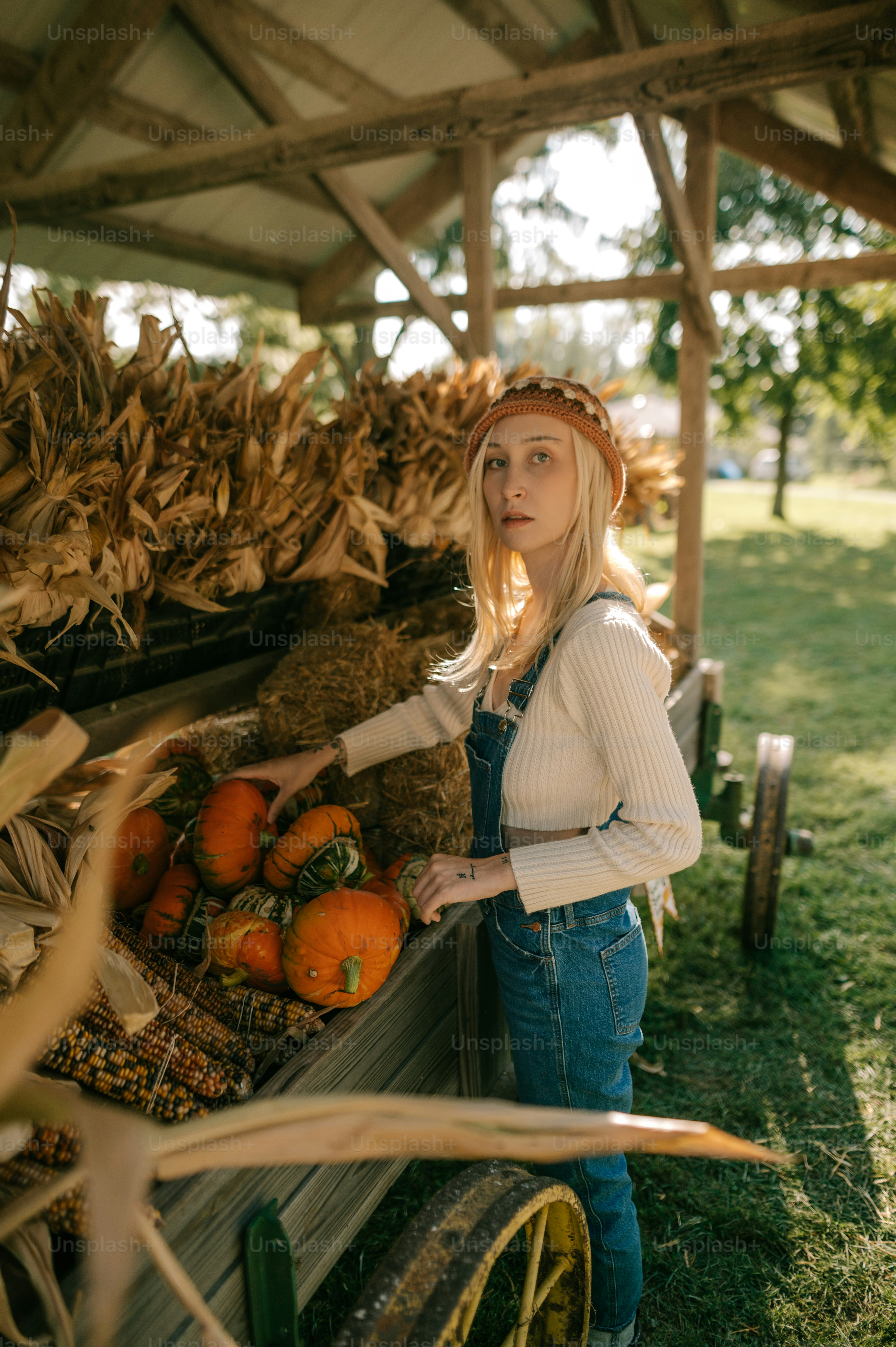 a woman standing next to a wagon filled with pumpkins
