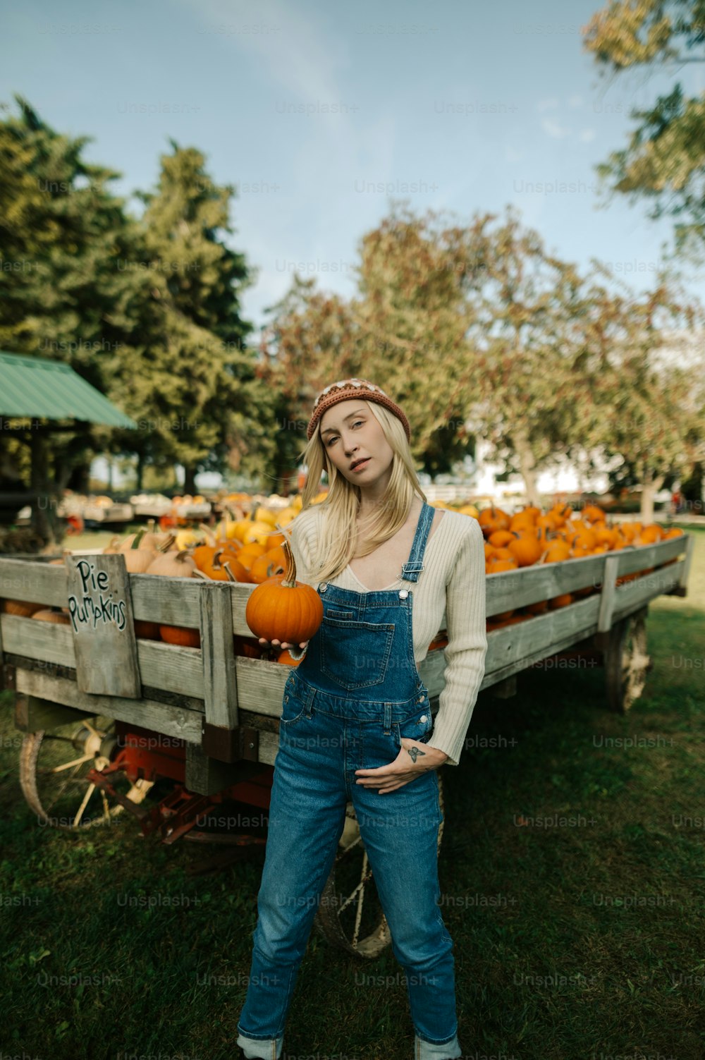a woman standing in front of a wagon full of pumpkins