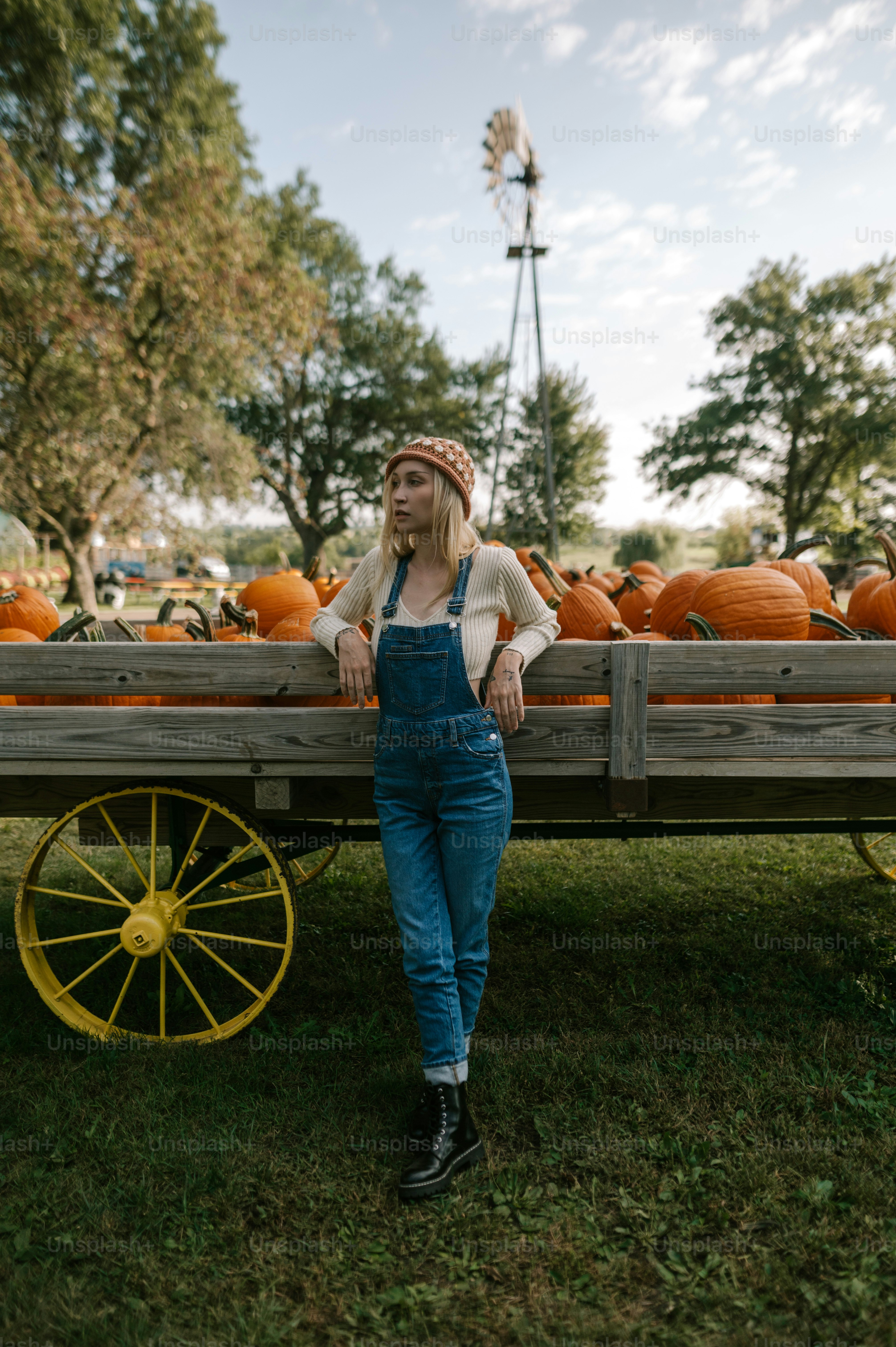 a woman standing next to a wagon filled with pumpkins