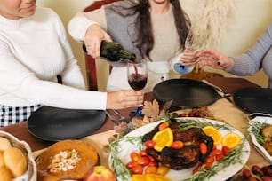 Un grupo de mujeres sentadas alrededor de una mesa con comida y vino