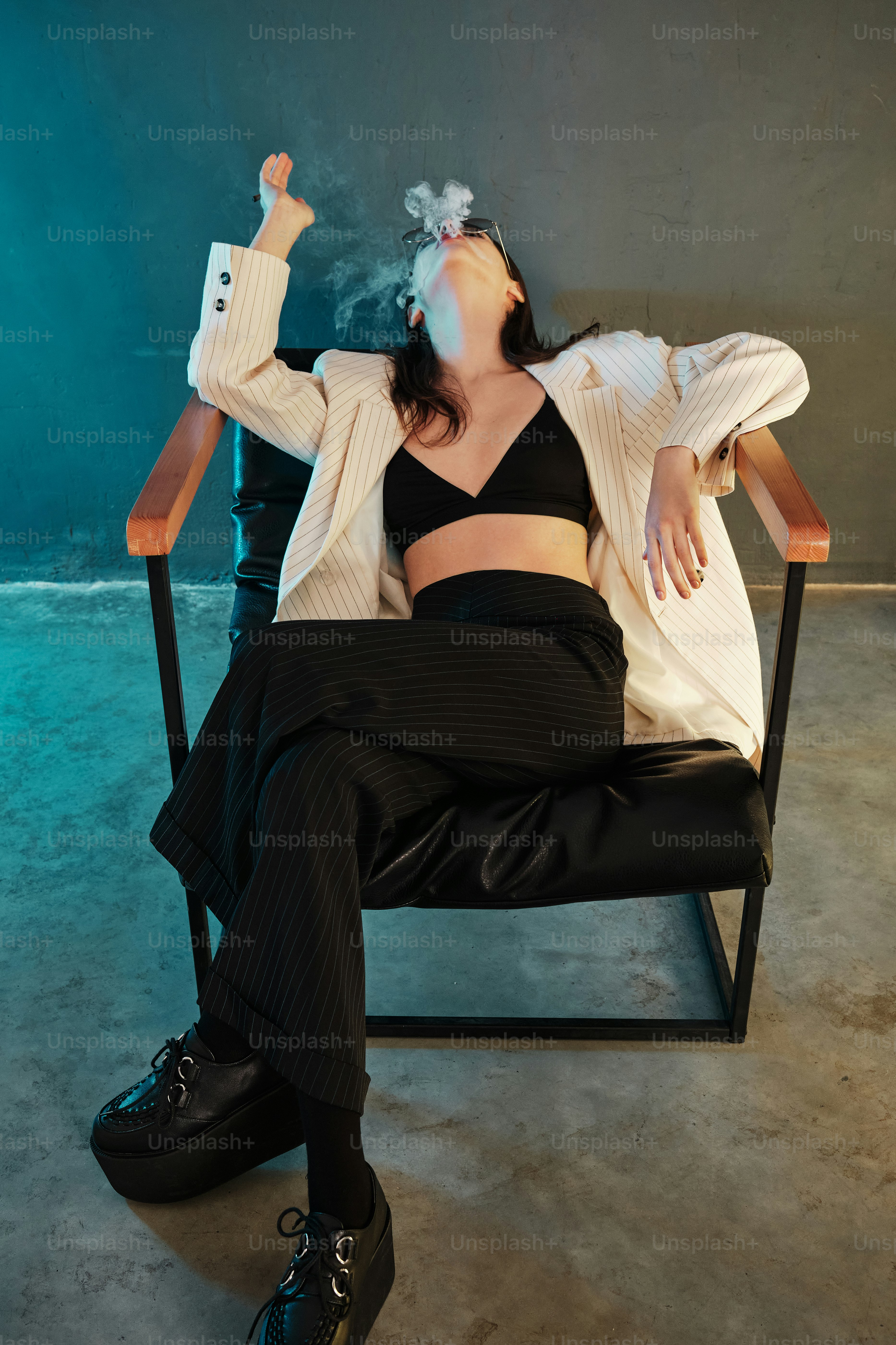 a woman sitting in a chair smoking a cigarette