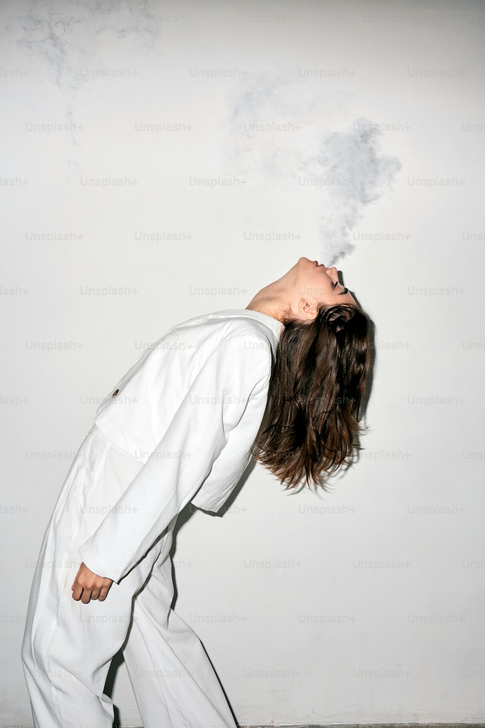 a woman in a white suit is smoking a cigarette