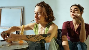 a man and a woman sitting at a table smoking cigarettes