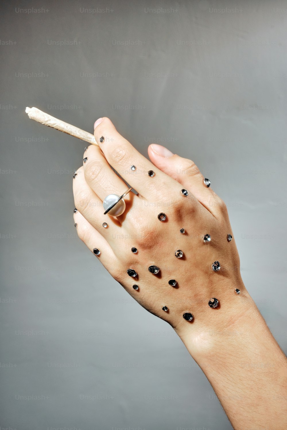 a woman's hand holding a cigarette with holes on it