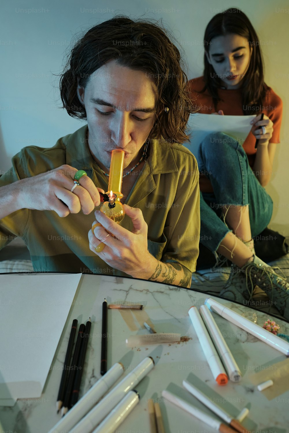 a woman sitting at a table with a cigarette in her mouth