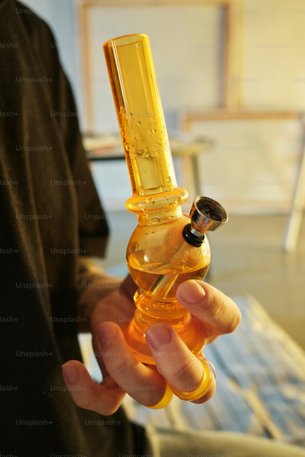 a person holding a glass pipe with a liquid inside of it