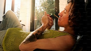 Un hombre fumando un cigarrillo en un sofá