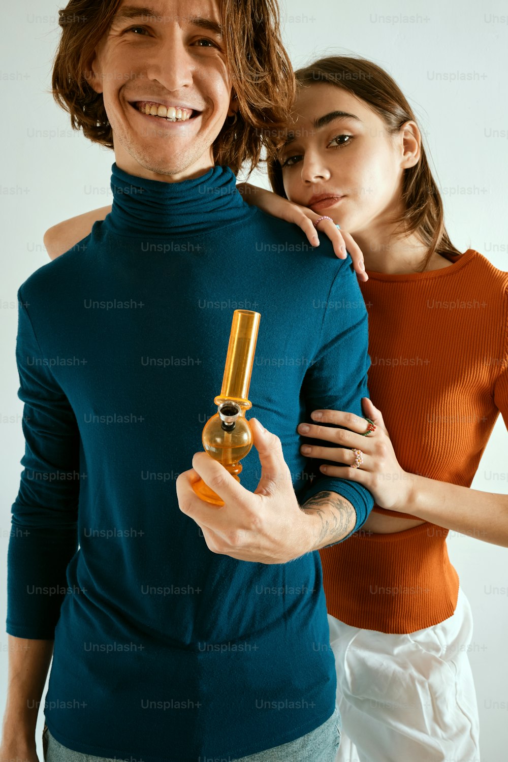 um homem segurando um frasco de perfume ao lado de uma mulher