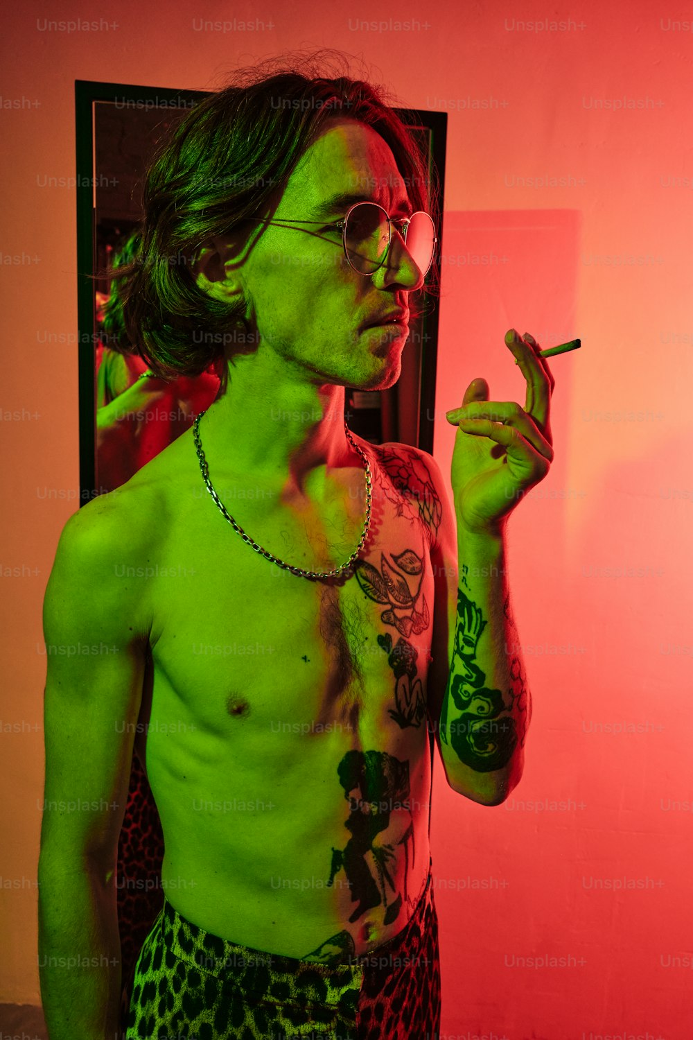 a shirtless man smoking a cigarette in front of a mirror