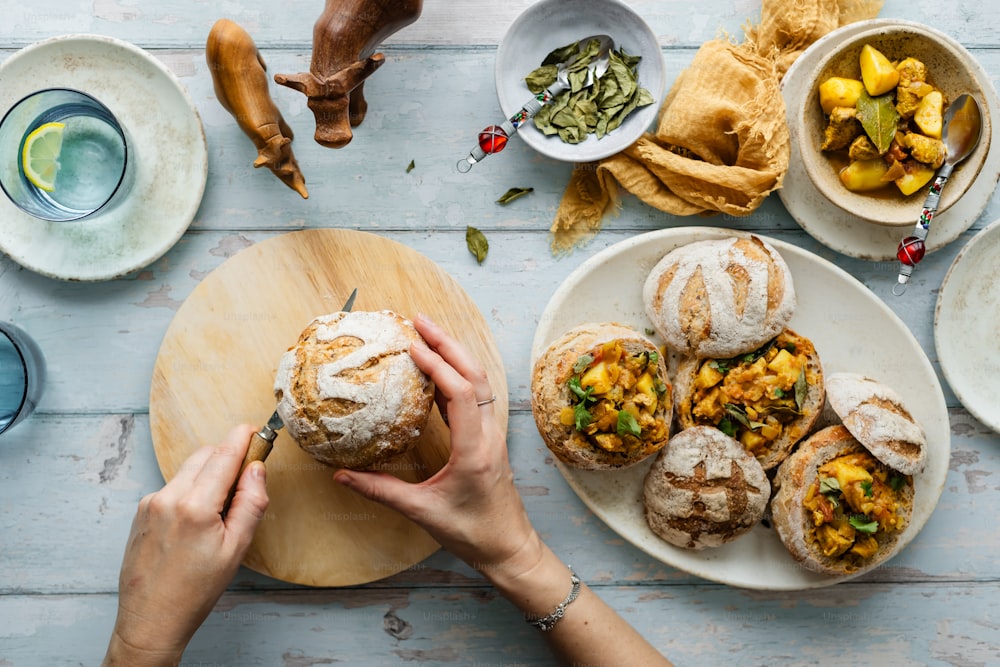 a person holding a piece of bread over a plate of food