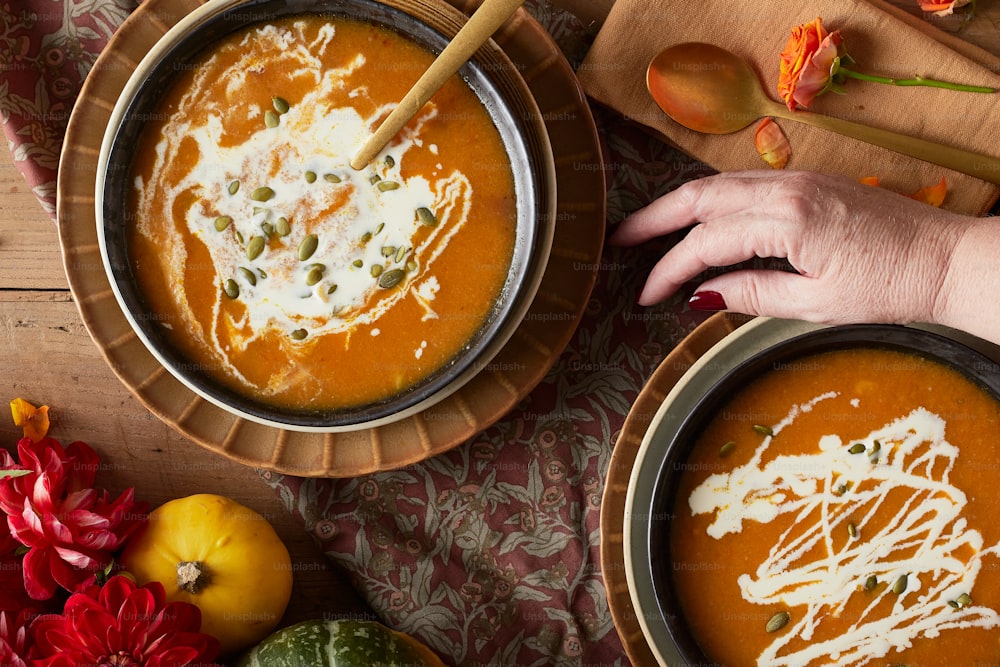 two bowls of pumpkin soup with a spoon in one