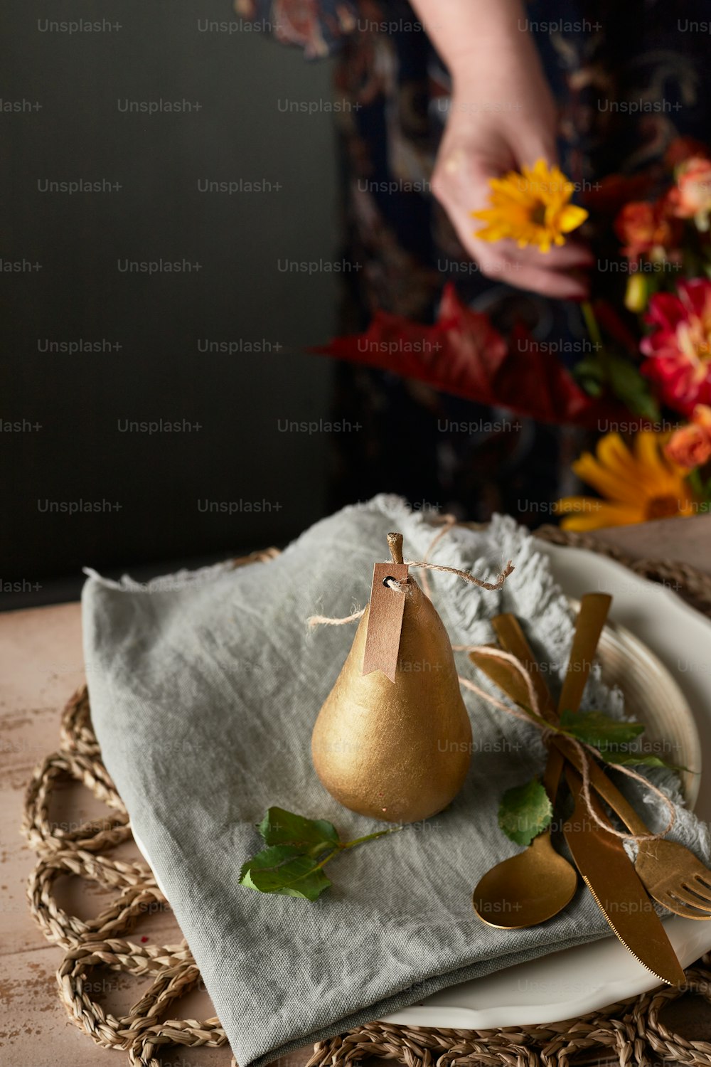 a plate with a pear on it next to a vase of flowers