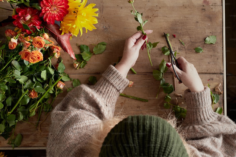 une personne coupant des fleurs avec des ciseaux sur une table