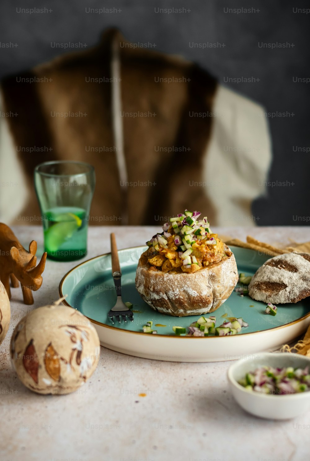 a plate of food on a table with a dog in the background