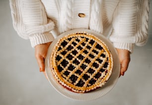 a person holding a plate with a pie on it