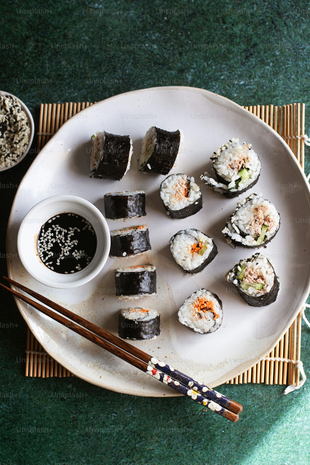 um prato branco coberto com sushi e pauzinhos