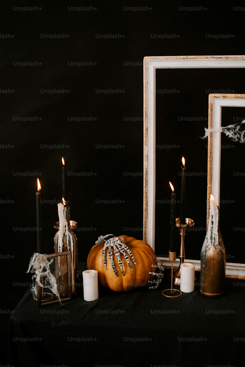 una mesa negra cubierta con velas y una calabaza