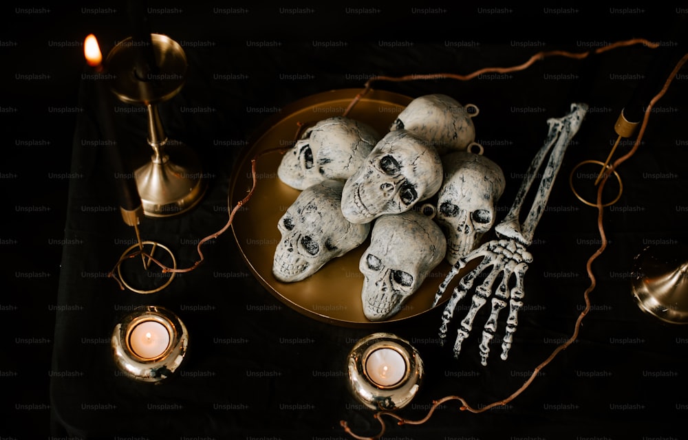 une table surmontée d’une assiette de crânes et de bougies