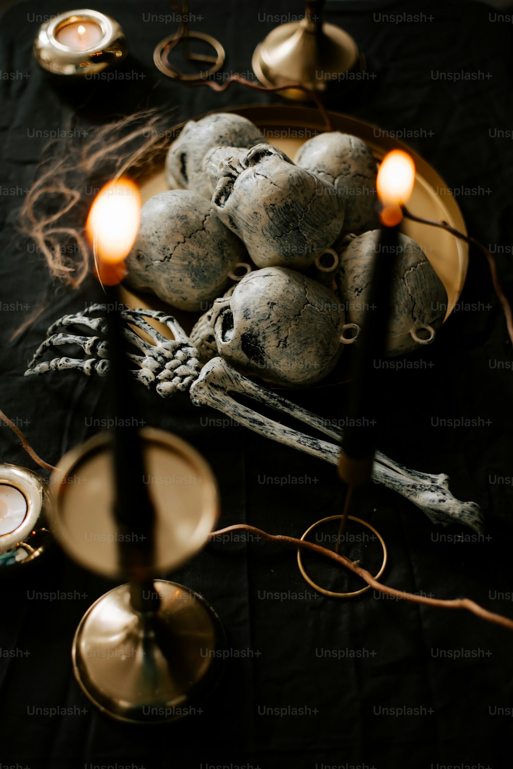 una mesa coronada con un plato de calaveras y velas