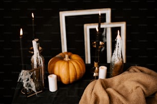 a black table topped with candles and a pumpkin
