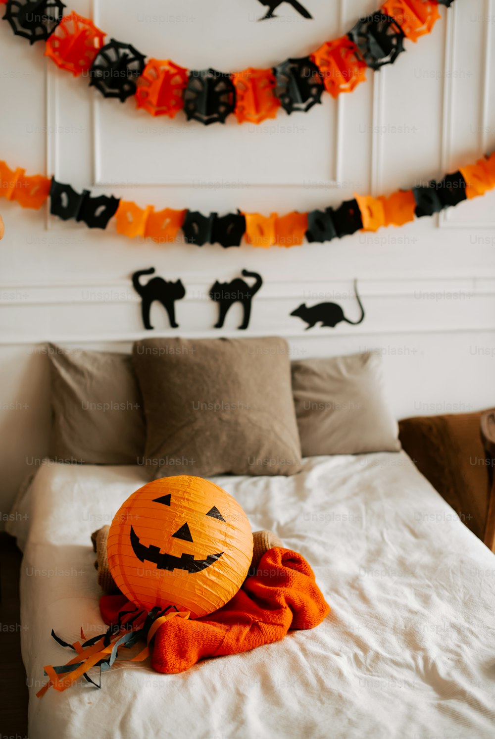 a pumpkin sitting on a bed with a halloween decoration