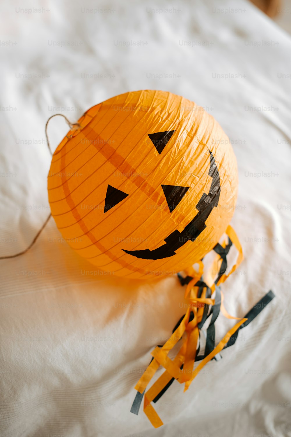 a paper lantern shaped like a pumpkin on a bed