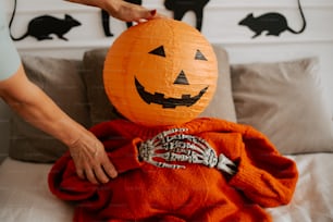a person holding a pumpkin on top of a bed