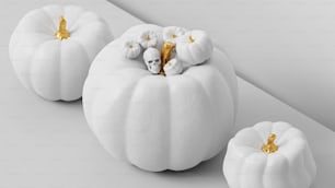 three white pumpkins with gold decorations on them
