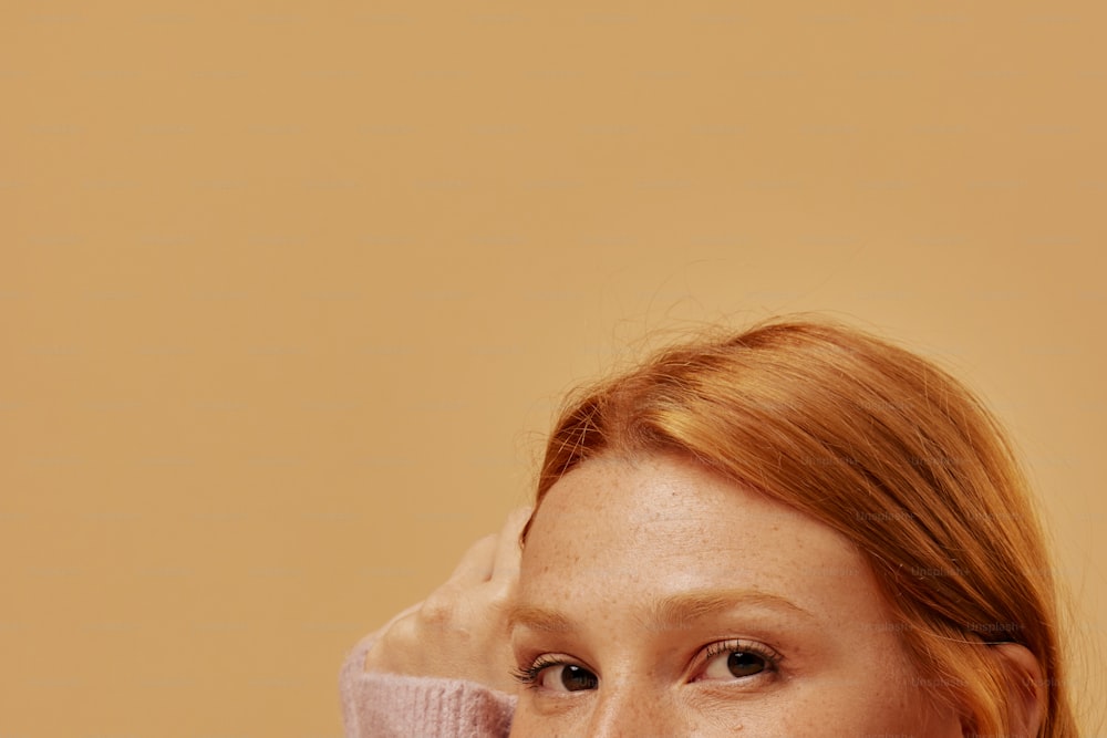 a woman with red hair wearing a pink sweater