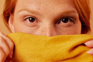 a woman covering her face with a yellow cloth