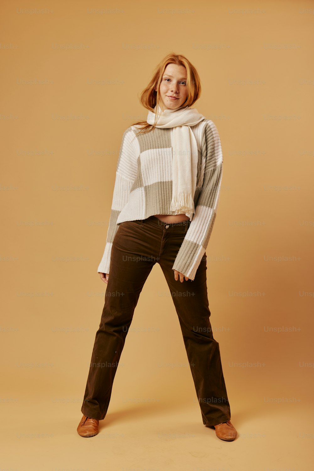 a woman in a white sweater and brown pants