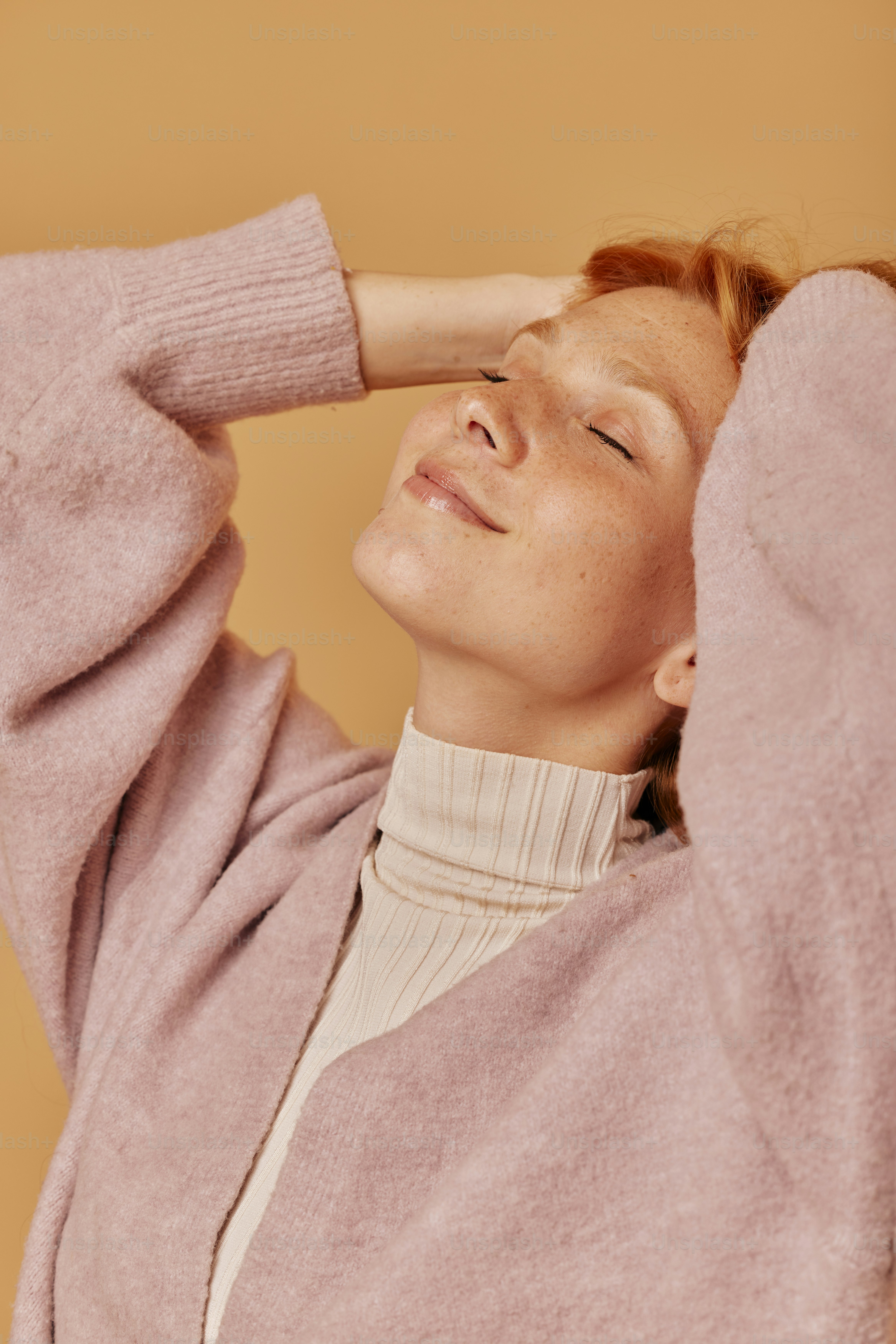 Una donna con i capelli rossi che indossa un maglione rosa