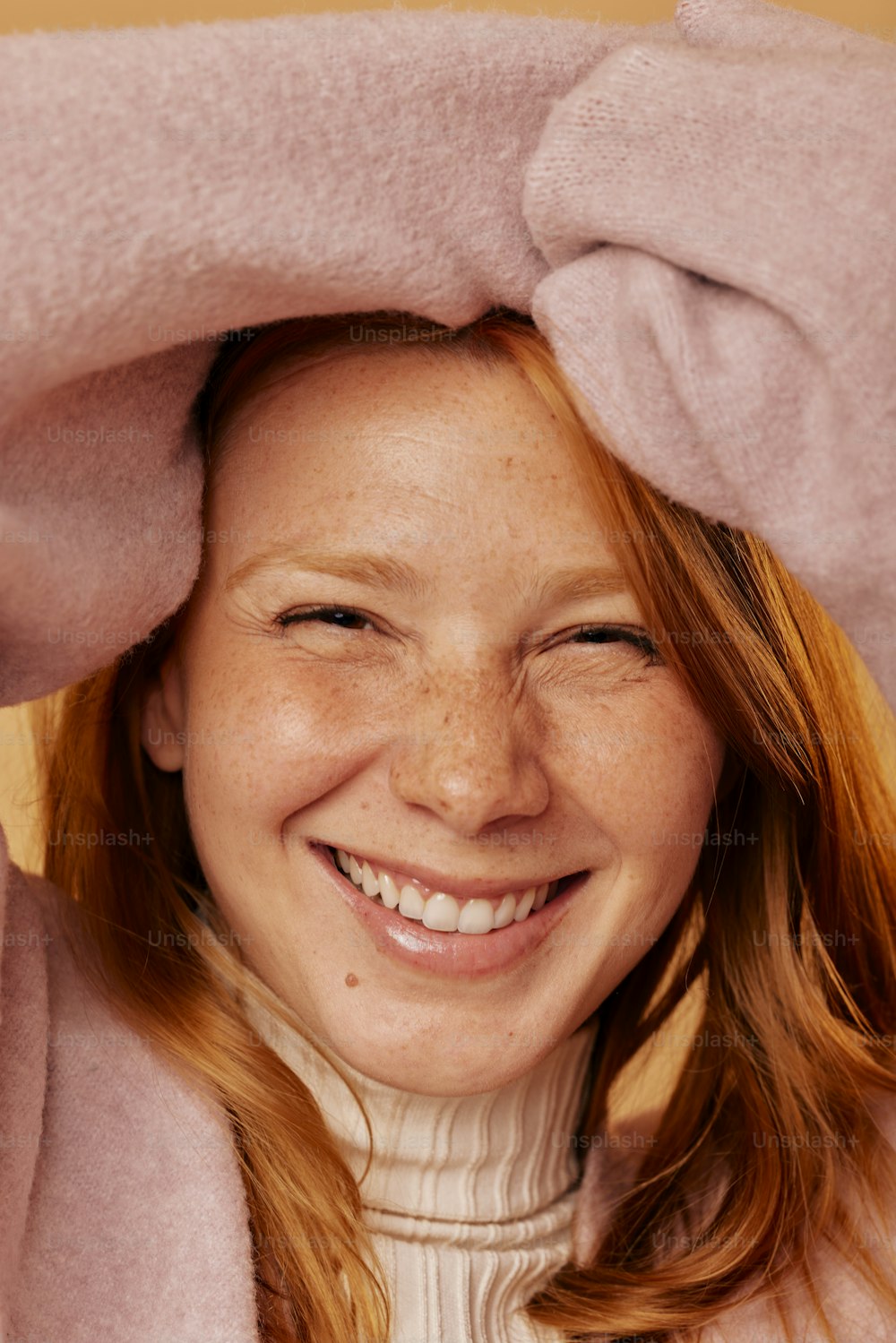 a woman is smiling under a pink blanket