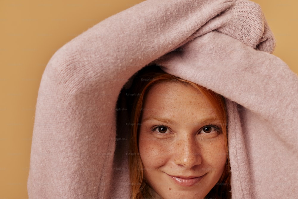a woman under a pink blanket smiling at the camera