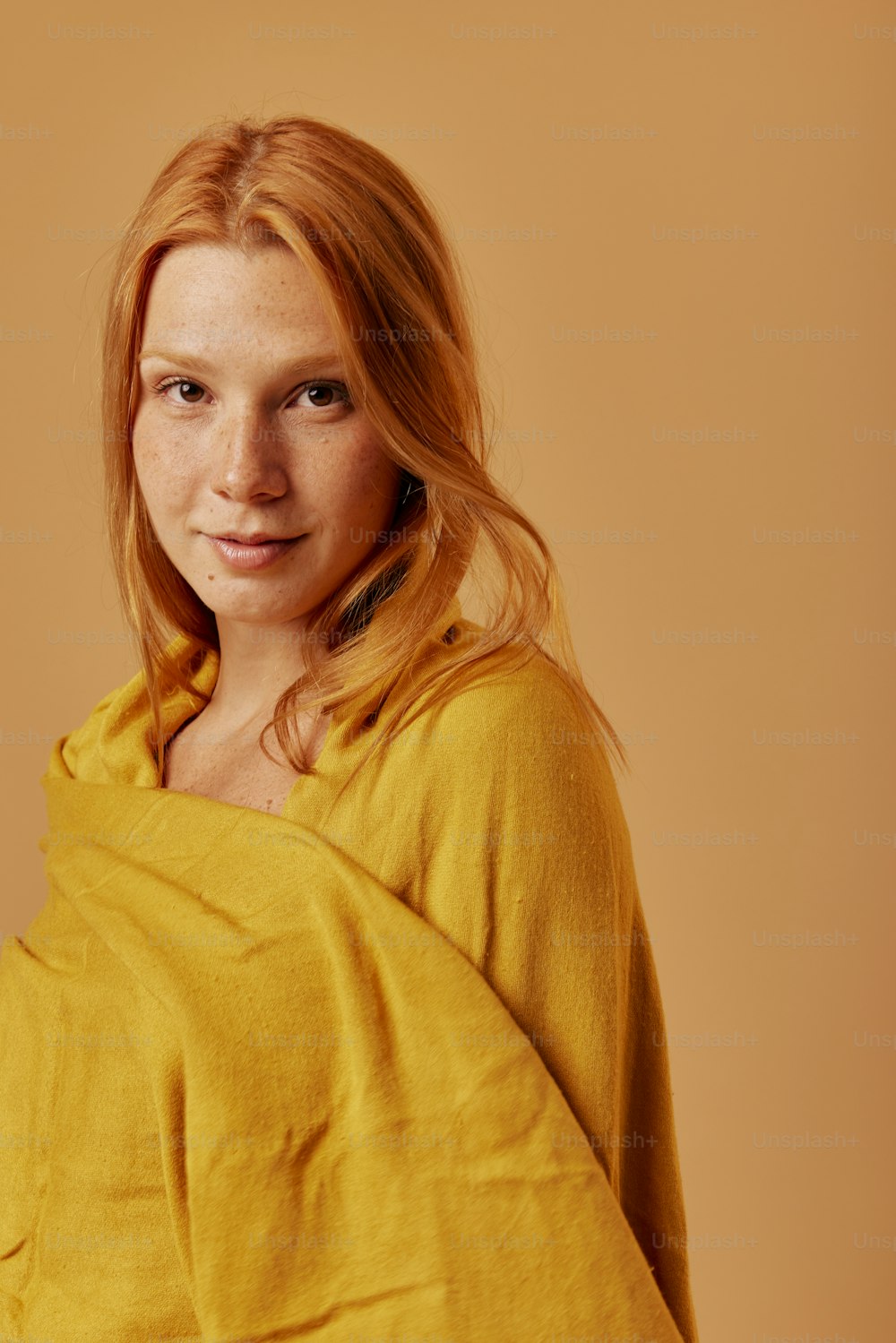 eine Frau mit roten Haaren, eingewickelt in eine gelbe Decke