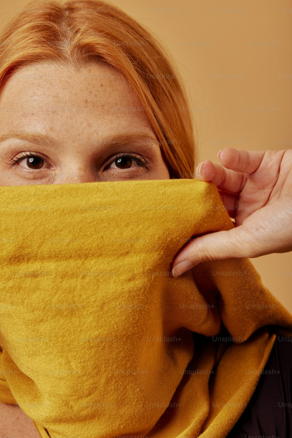 a woman covering her face with a yellow scarf
